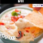 a ceramic bowl full of white queso dip with nacho dipped in with text