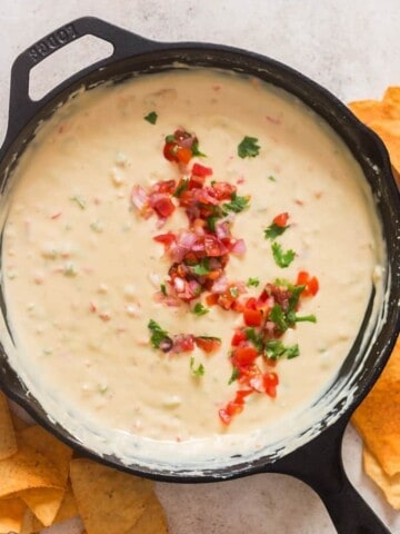 queso dip cooked in cast iron skillet with fresh pico de gallo garnish