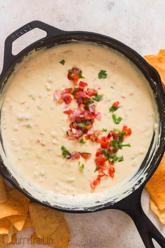 queso dip cooked in cast iron skillet with fresh pico de gallo garnish