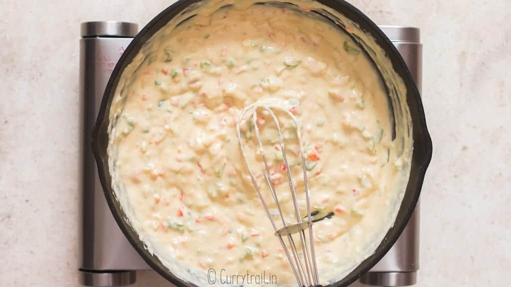 whisking queso sauce in a cast iron pan.