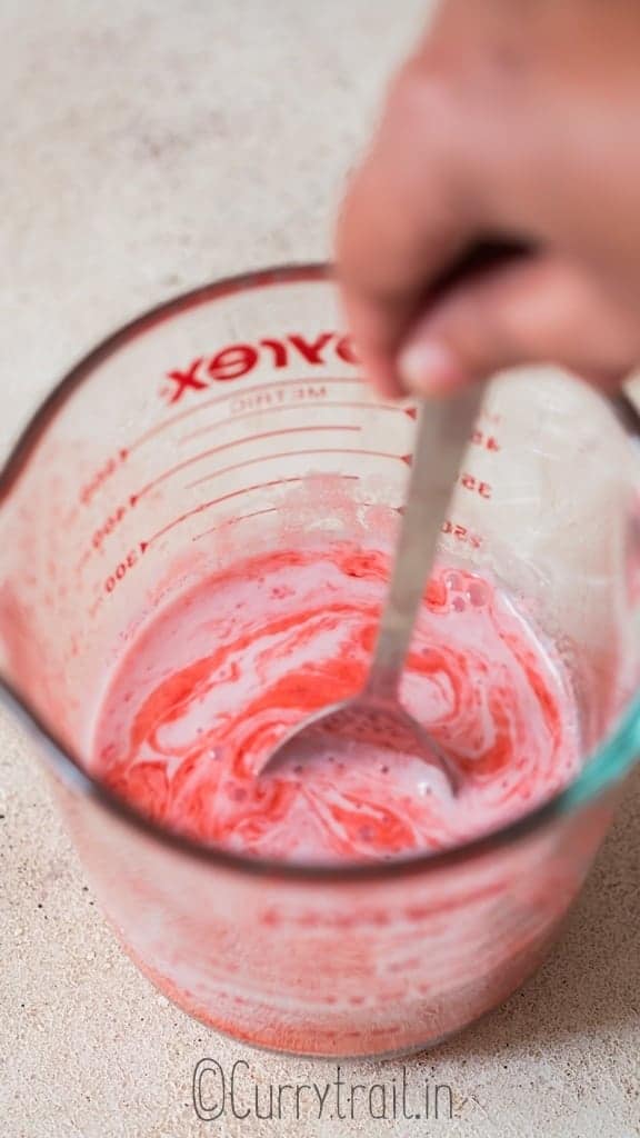 stirring strawberry milk in glass