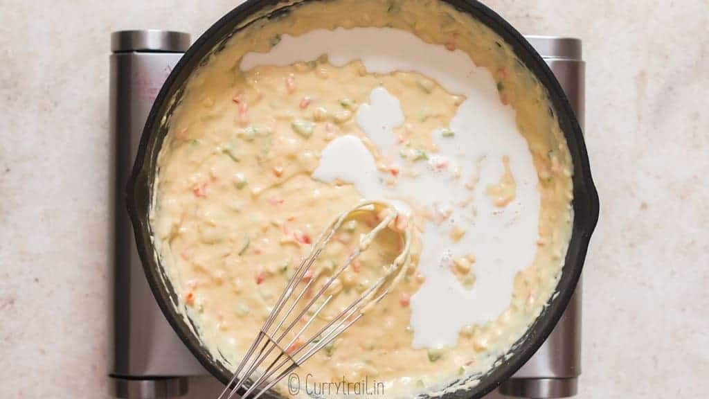 whisking in evaporated milk to white queso dip in a skillet.