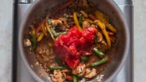 diced tomatotes along with vegetables in skillet to make cajun chicken pasta