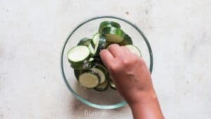 salting zucchini slices in bowl