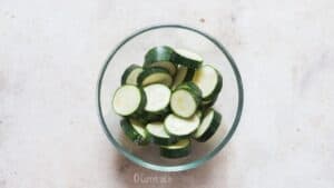 salting zucchini slices in bowl