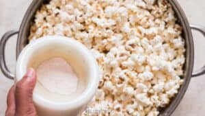 adding popcorn salt to freshly popped popcorn