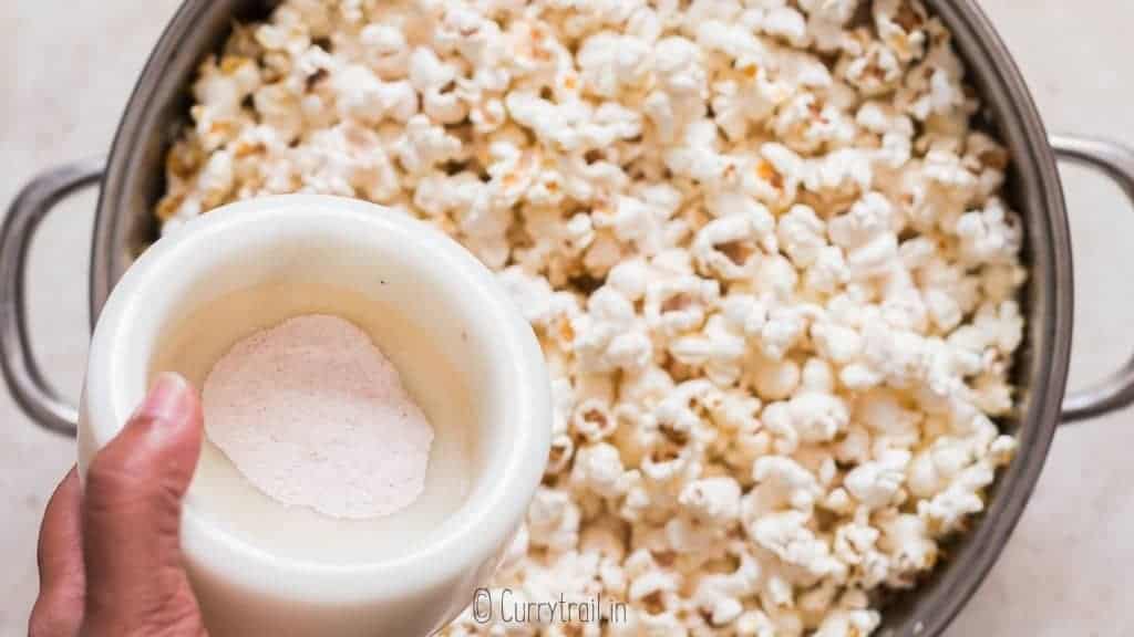 adding popcorn salt to freshly popped popcorn