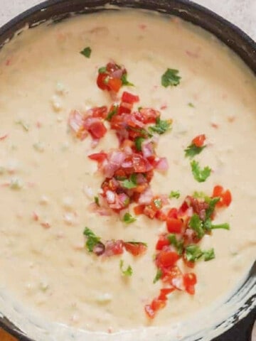 white queso dip in a cast iron skillet with chips on the side.