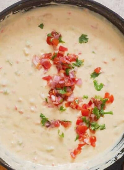 white queso dip in a cast iron skillet with chips on the side.