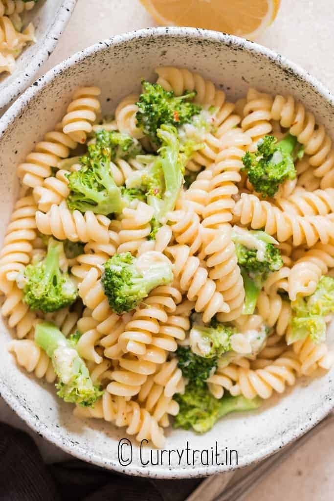 broccoli fusilli pasta served in a bowl with lemon on the side.