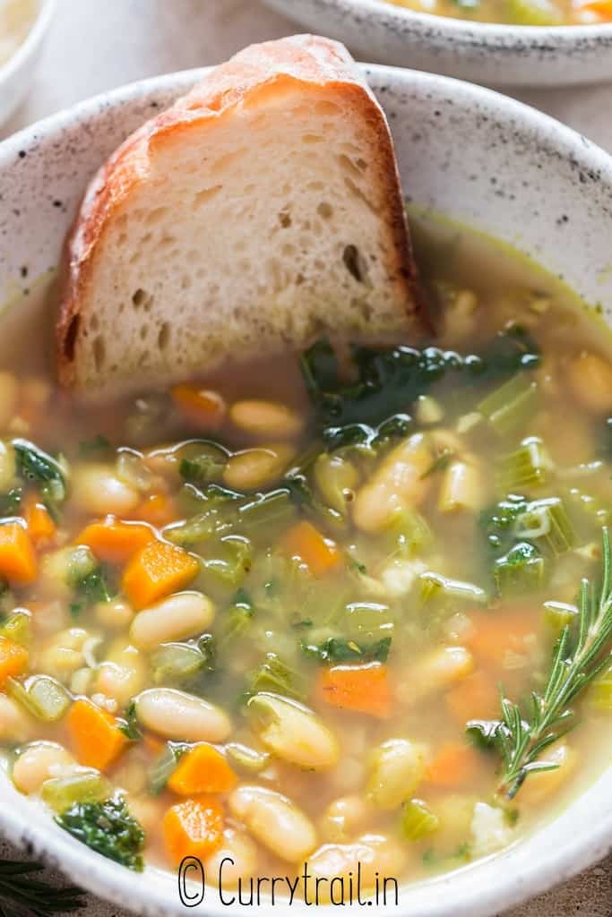 close up view of a bowl of white bean soup with bread