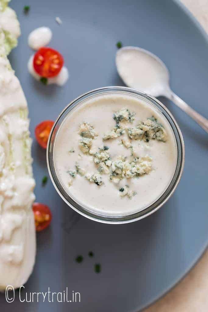 salad dressed with homemade creamy blue cheese dressing in a jar on ceramic plate