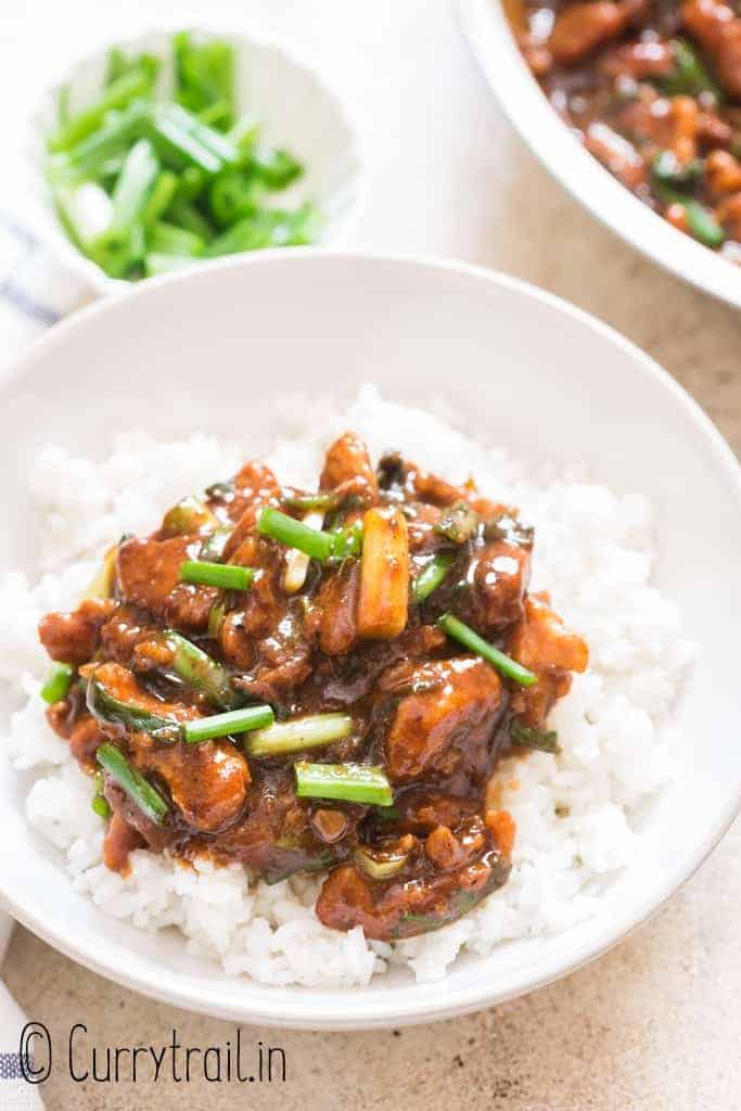 dark brown saucy Mongolian chicken served with rice in ceramic bowl