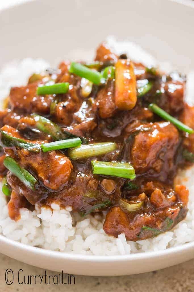 dark brown saucy Mongolian chicken served with rice in ceramic bowl