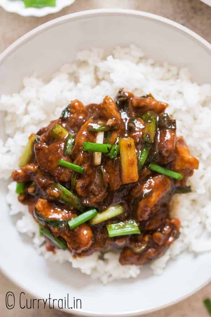 dark brown saucy Mongolian chicken served with rice in ceramic bowl
