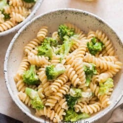 broccoli fusilli pasta served in two ceramic bowl with lemon on side