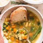 white bean and kale soup served in two ceramic bowl with crusty bread
