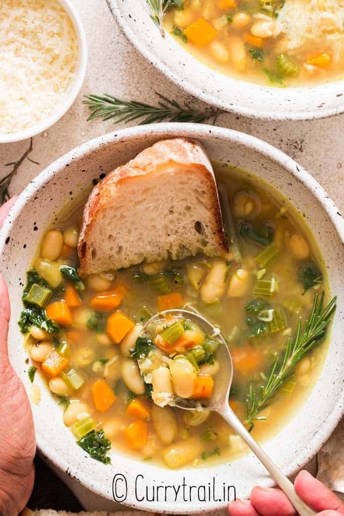 white bean and kale soup served in two ceramic bowl with crusty bread