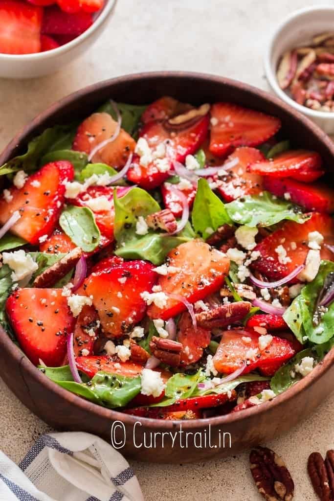 spinach and strawberry salad in wooden salad bowl