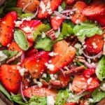 spinach and strawberry salad in wooden bowl with poppy seed dressing