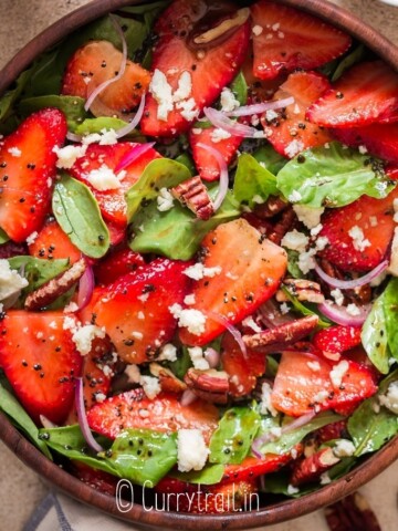 spinach and strawberry salad in wooden bowl with poppy seed dressing