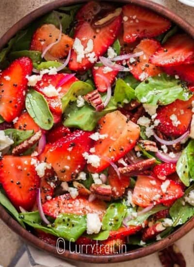 spinach and strawberry salad in wooden bowl with poppy seed dressing