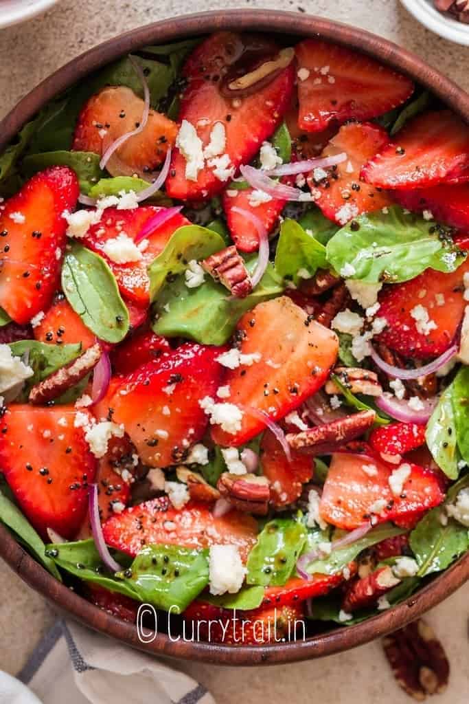 spinach and strawberry salad in wooden bowl with poppy seed dressing