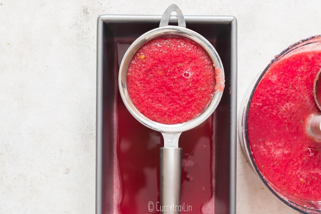 filtering watermelon juice through a fine mesh sieve.