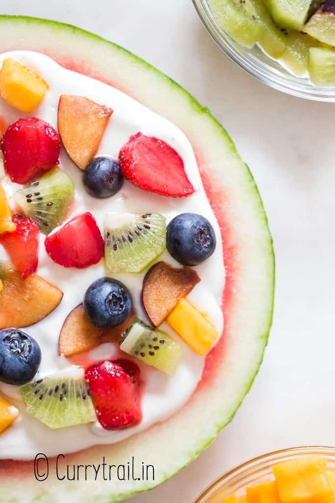 close up view of watermelon pizza with cheesecake frosting and fruits