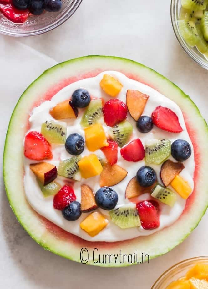thick slice watermelon pizza with cheesecake frosting and fruits
