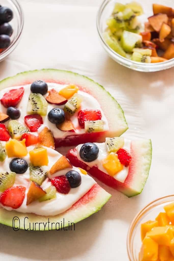 thick slice of watermelon pizza with cheesecake frosting and fruits