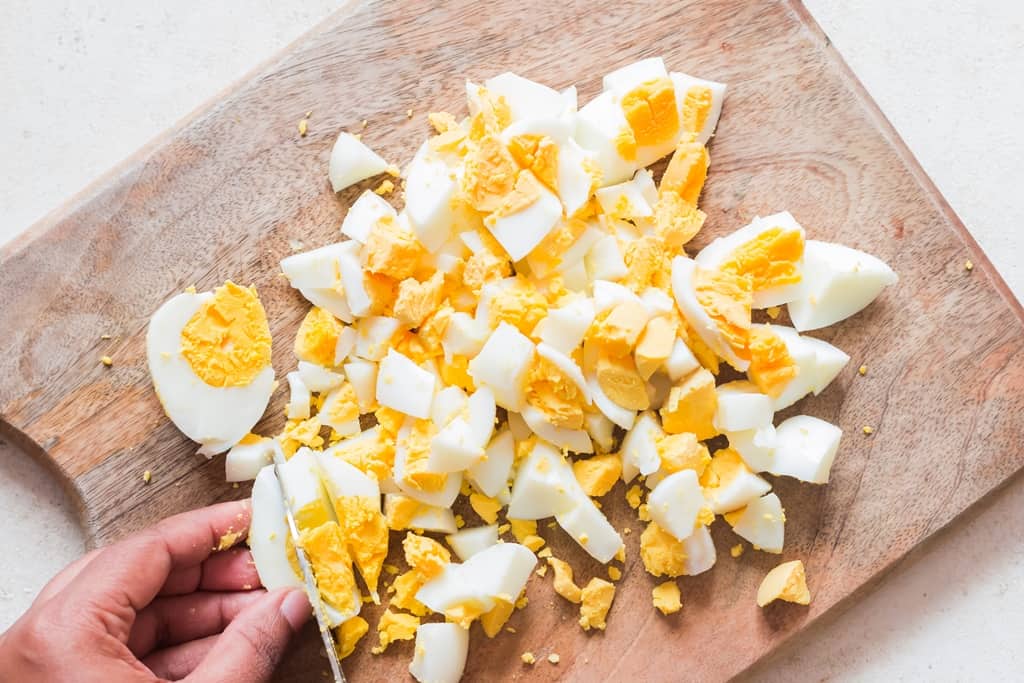 chopping hard-boiled eggs on a wooden board.