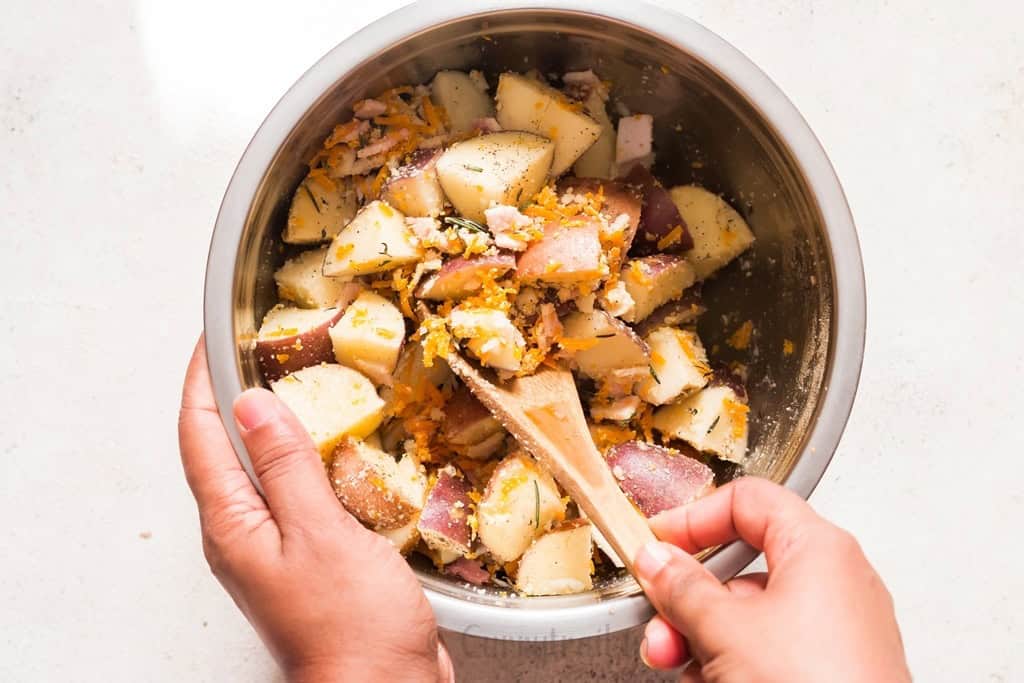 mixing diced potatoes with cheese in a bowl.
