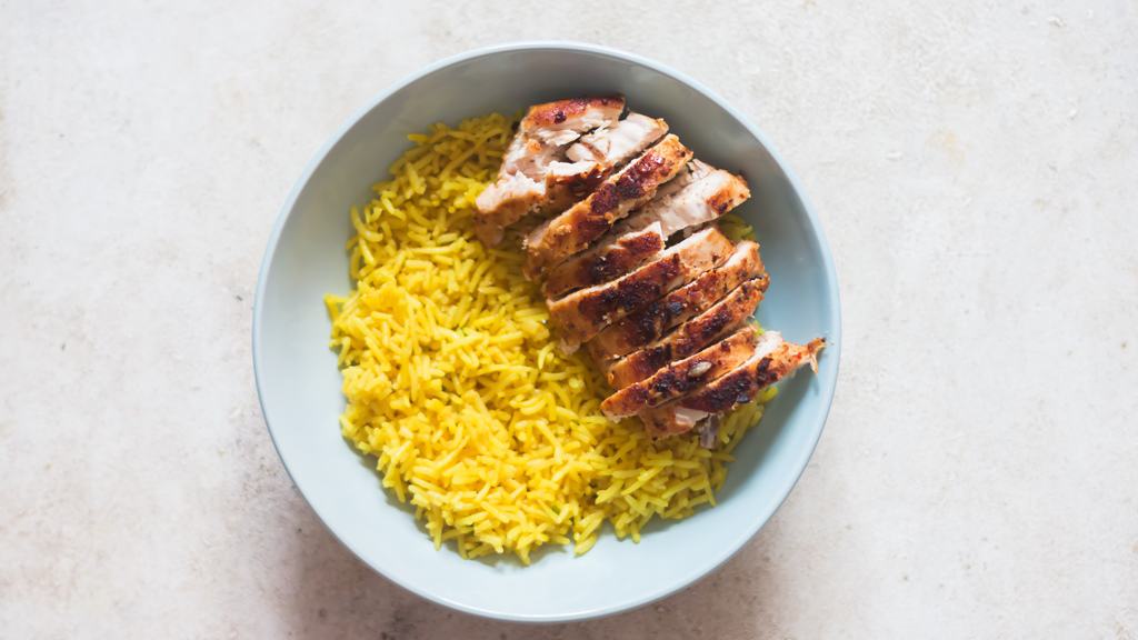 assembling chicken shawarma bowl with yellow rice