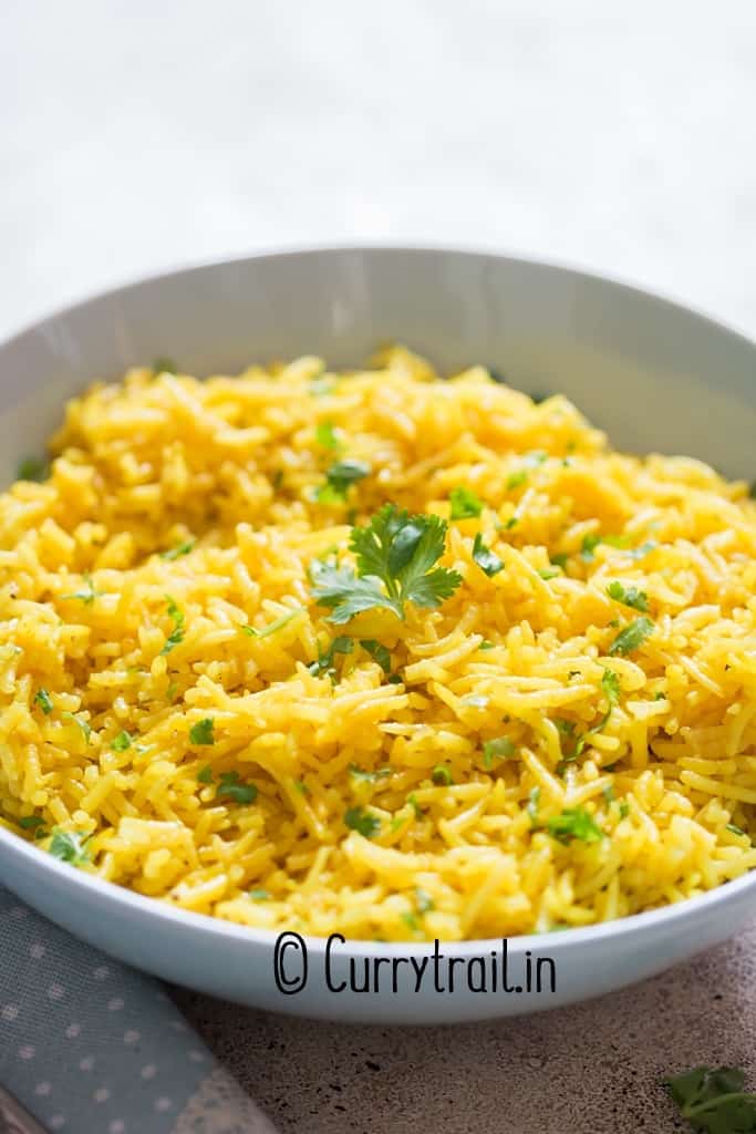 yellow turmeric rice in a bowl garnished with parsley.