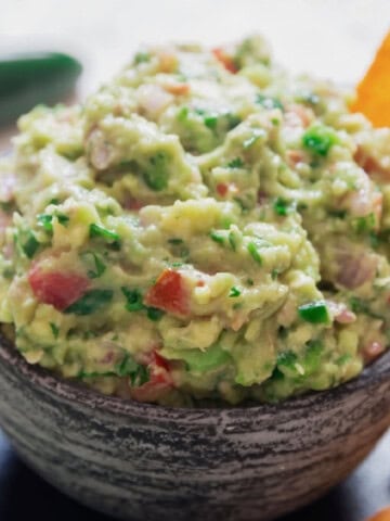 guacamole in a bowl with nacho chips.