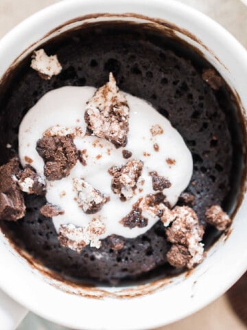 1 minute oreo mug cake with whipped cream and oreo crumbs on top