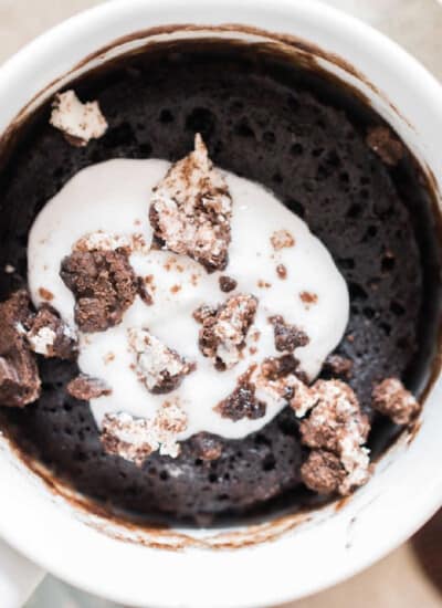 1 minute oreo mug cake with whipped cream and oreo crumbs on top