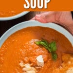 thick tomato soup with basil leaves in a bowl with text.