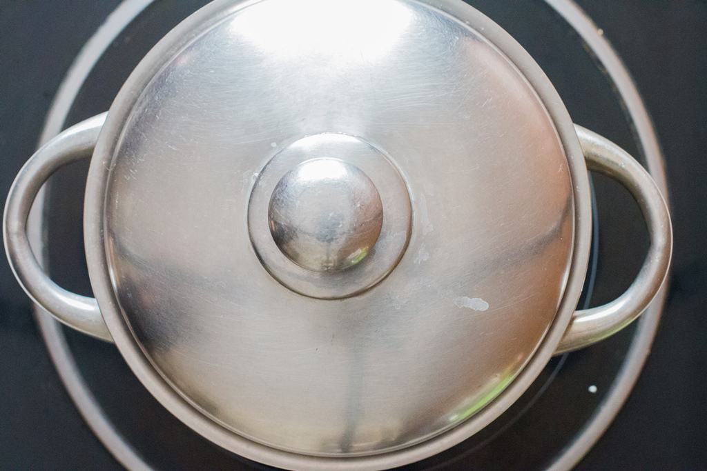 steaming rice in a saucepan on the stove top with the lid closed.