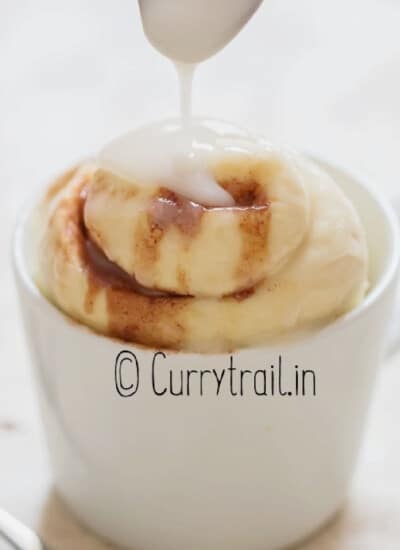 cinnamon roll in a mug with sugar glaze poured on top.