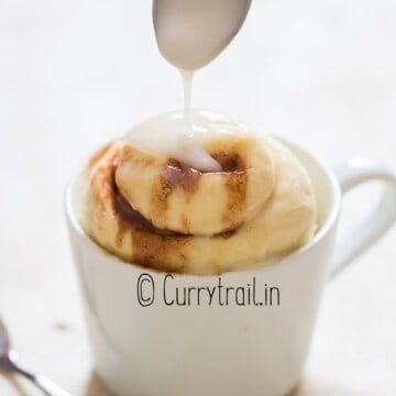 microwave cinnamon roll in a mug with glaze