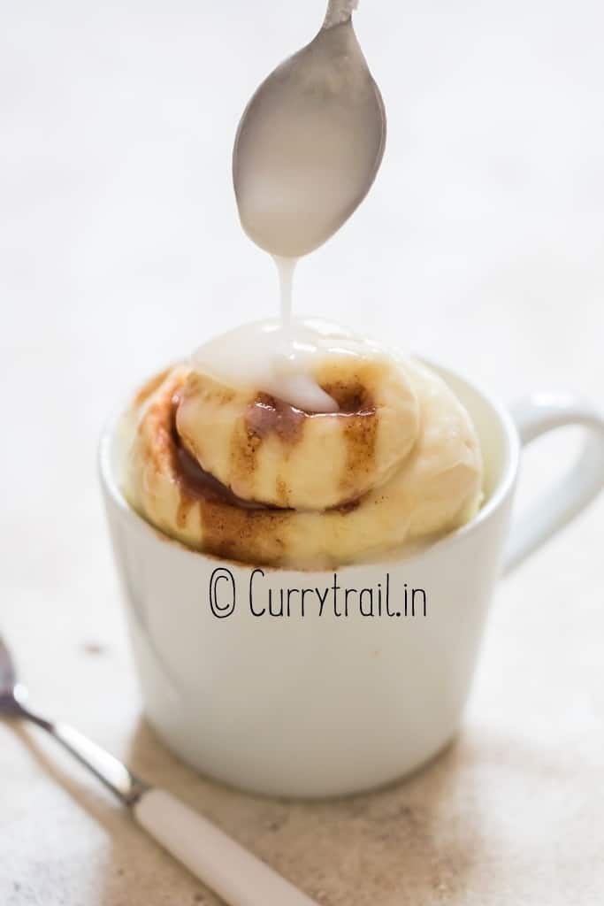 microwave cinnamon roll in a mug with glaze
