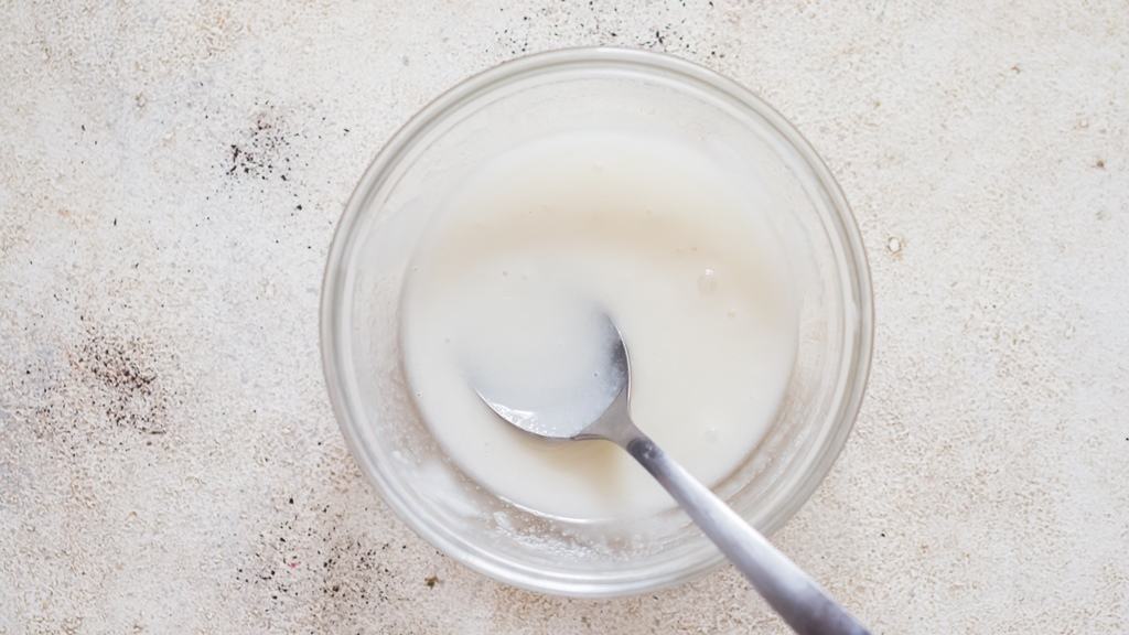 making sugar glaze by mixing confectioners sugar and milk in a small bowl.