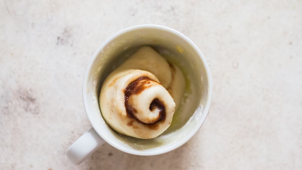 cinnamon roll placed inside a microwave mug.