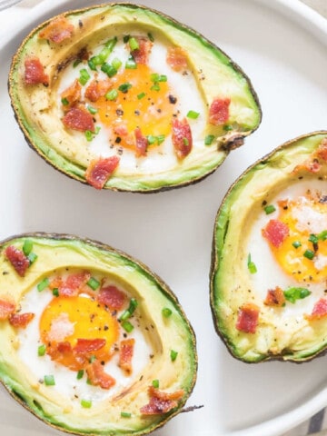 3 baked avocado eggs on white plate