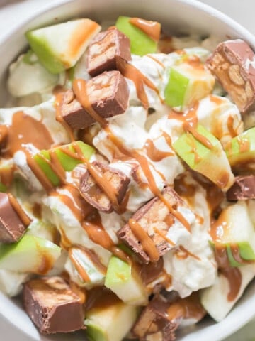 caramel drizzled apple snickers salad in a bowl