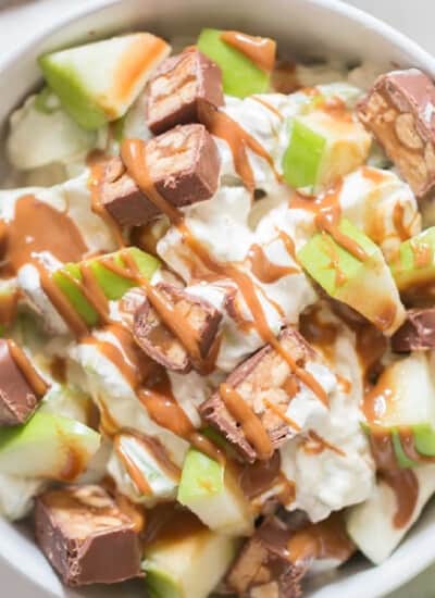 caramel drizzled apple snickers salad in a bowl