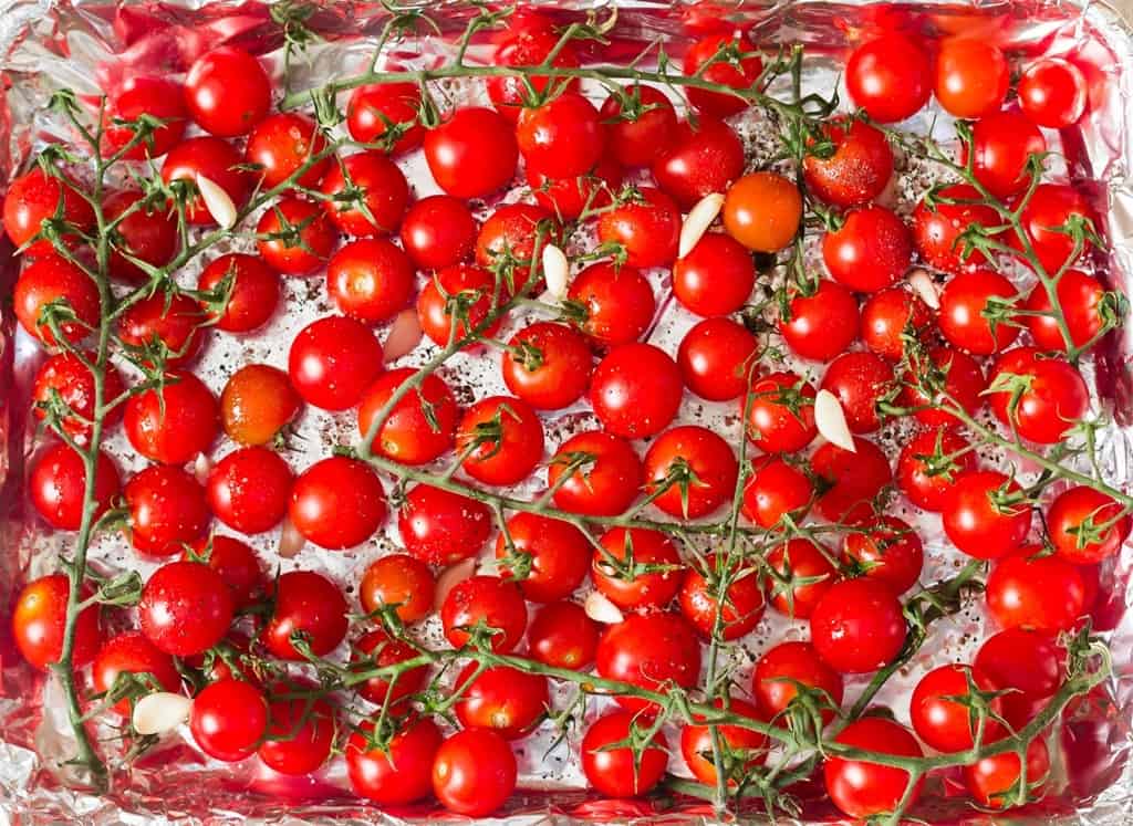 cherry tomatoes on the vine arranged on baking tray.