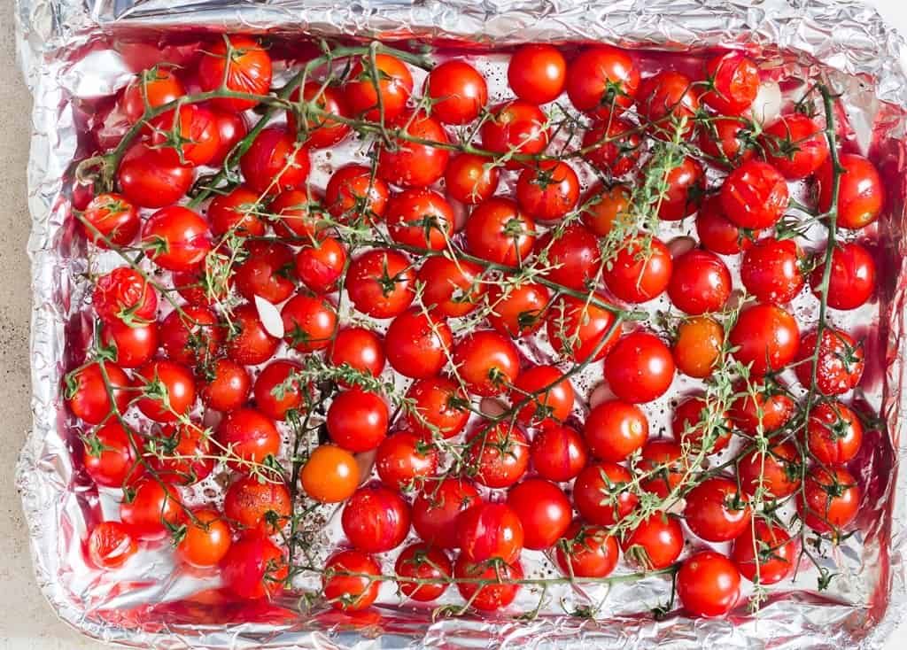 cherry tomatoes on the vine arranged on baking tray.